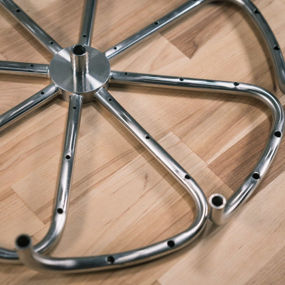 Et nærbilde av Ss Brewtech Manifold | Mash Re-Circulation for 75L vannkokere, med flere buede eiker og hull, laget av 304 rustfritt stål med en diameter på 39 cm, hvilende på tre.