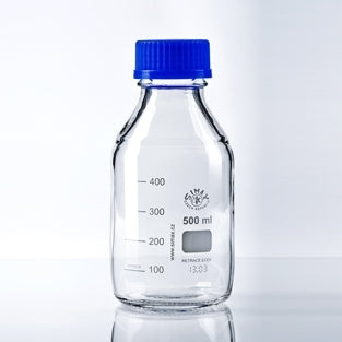 Heco Flaske 500ml av 3.3 borosilikatglass med blå kork, markert med målestreker, plassert på reflekterende underlag mot enkel bakgrunn. Perfekt som laboratorieflaske eller til rehydrering av tørrgjær.