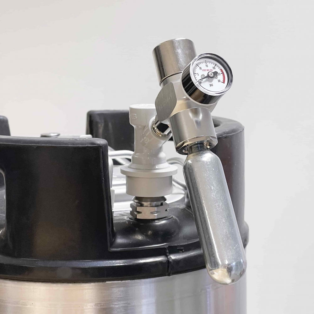 Nærbilde av Project Brew CO2 Picnic Regulator med manometer festet til et fat i rustfritt stål, vist mot en vanlig hvit bakgrunn.