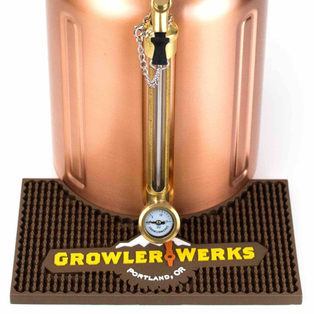 Et uKeg 128 oz GrowlerWerks-fat i kobber med trykkmåler står på en uKeg 128 Bar Mat med påskriften «GrowlerWerks Portland, OR».