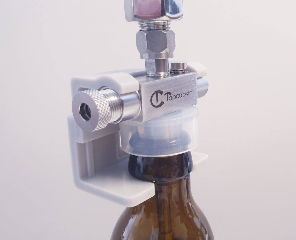 Tapcooler Handsfree Clip, en anordning i metall og plast, festes på toppen av en brun glassflaske for kontrollert fylling eller kapsling.
