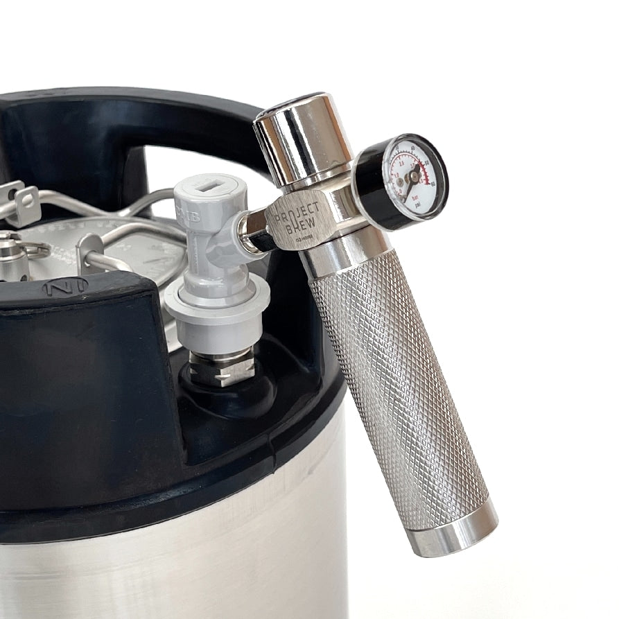 Project Brews miniregulator for ølgass er festet til en hvit kulelås på toppen av et metallfat.
