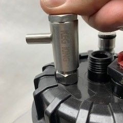 En hånd fester et beslag i rustfritt stål SS316 til en svart gjenget plasthette med andre beslag, inkludert Keg King Quickie - Cornelius Post Dispenser.