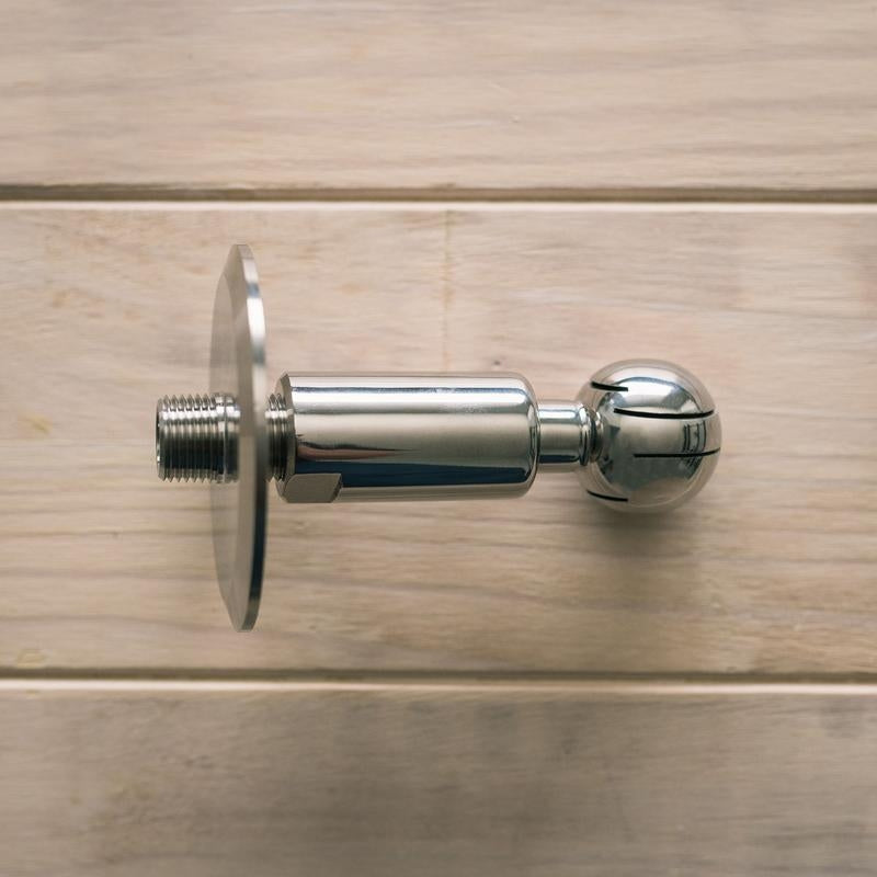 En Brewshop CIP Roterende Vaskeball 3" TC x 1/2" NPT laget av 304 rustfritt stål hviler på en treflate.