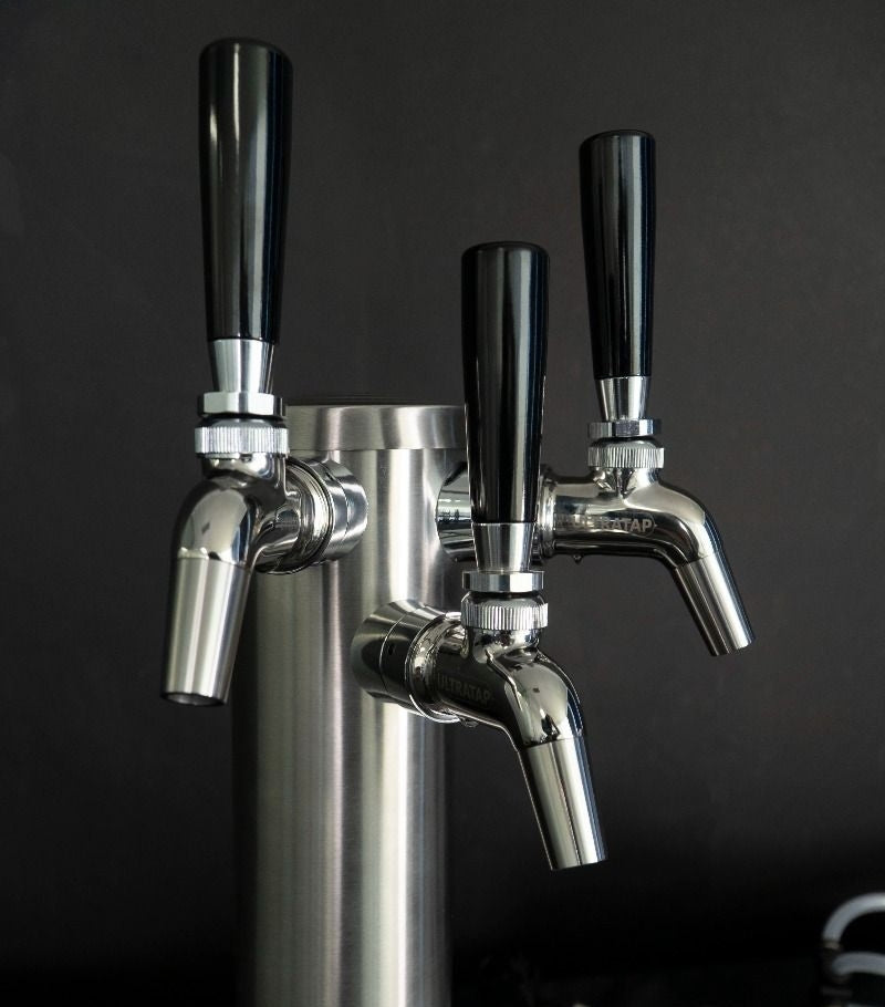 Keg King FasTap Font Kit tappetårn sett med 3 kraner har tre kraner med svart håndtak - perfekt for øltapping hjemme - her vist mot en mørk bakgrunn.