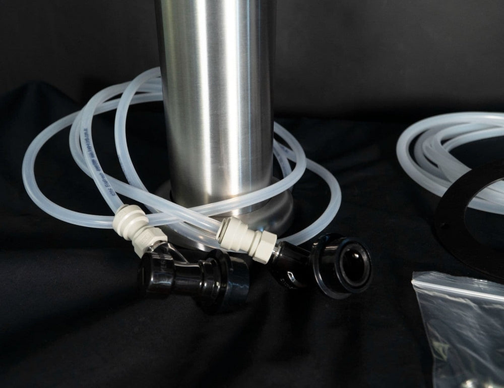 Keg King FasTap Font Kit - Tappetårn sett med 2 kraner har klare plastslanger og svarte koblinger festet til en beholder i rustfritt stål, perfekt for din kegerator - vist på en elegant svart overflate.