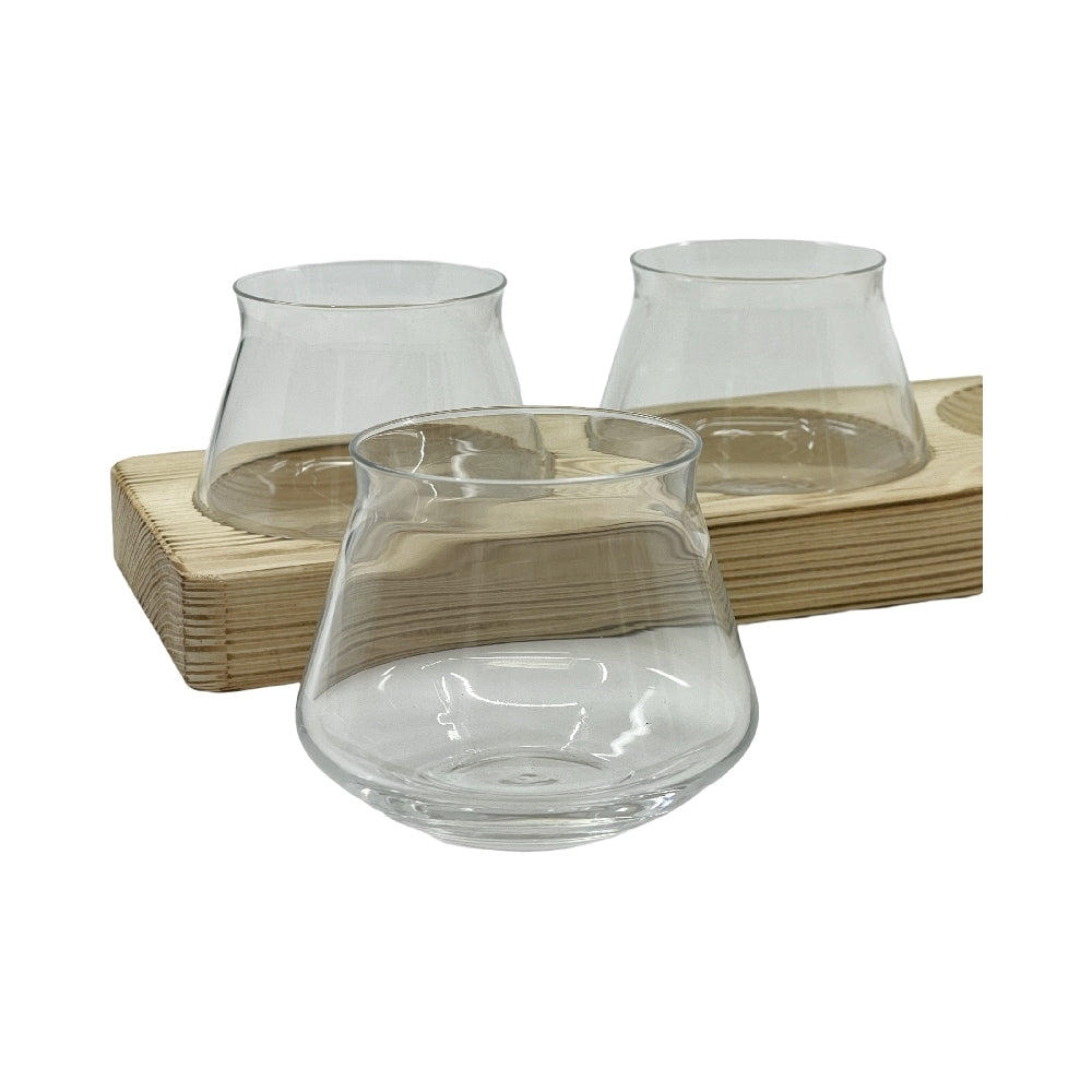 Tre klare, stilkfrie Rastal Teku Taster-smaksglass fra Rastal Teku Taster Flight Set - smaksglass og smaksplanke er vist, to på et smaksplankebrett og ett foran, alle vist mot en hvit bakgrunn.