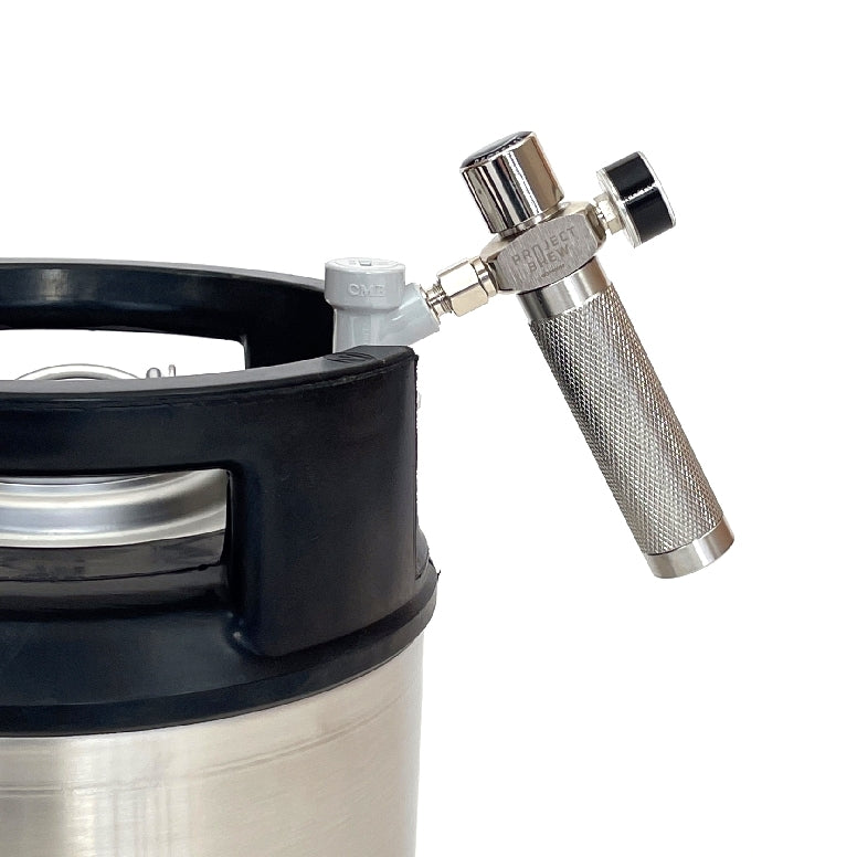 Nærbilde av et fat i rustfritt stål med Project Brew Beer Gas Mini Regulator og karbonatiseringshette i metall festet på toppen, klar til å karbonisere eller servere favorittbrygget ditt.