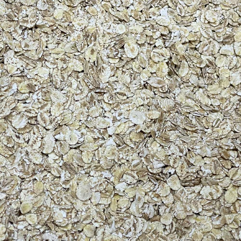 Et nærbilde av Flaket Bygg (Byggryn) - 100G fra Stangeland Mølle, som viser lys beige, flate byggflak - perfekt til maltblandinger eller sammen med havre i robuste oppskrifter.