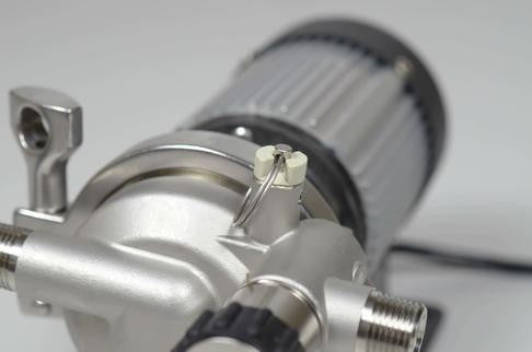 Nærbilde av Blichmann RipTide Brewing Pump, en metallisk industripumpe fra Blichmann, som viser ledninger og koblingskomponenter mot en vanlig bakgrunn.