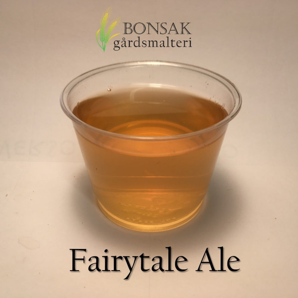 På en hvit flate står en gjennomsiktig kopp med lys ravfarget øl laget av Fairytale ALE Malt (6-9 EBC) 100G fra Bonsak Gårdsmalteri. "Bonsak Gårdsmalteri" og "Fairytale ALE Malt" står over og under koppen.