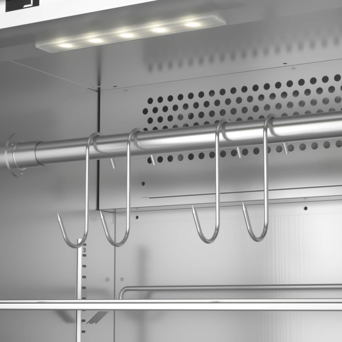 Et nærbilde av en metallstang med fire hengende kjøttkroker inne i et Caso DryAged Master 125 tørrmodningsskap, opplyst av en LED-lampe montert i taket.
