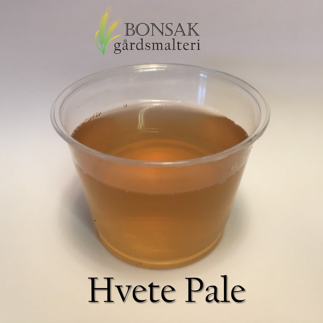 Et gjennomsiktig plastbeger inneholder en blek, ravfarget væske. Over står det "Bonsak Gårdsmalteri", og under står det "Hvete Pale Malt (6-8 EBC) 100G", som viser frem denne premium hvetemalten fra Bonsak Gårdsmalteri.