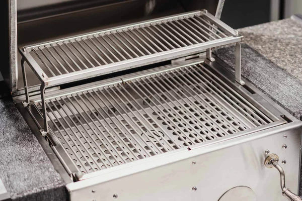 Nærbilde av en tom M Grills B24 Kullgrill av rustfritt stål med to stablede grillstativer.
