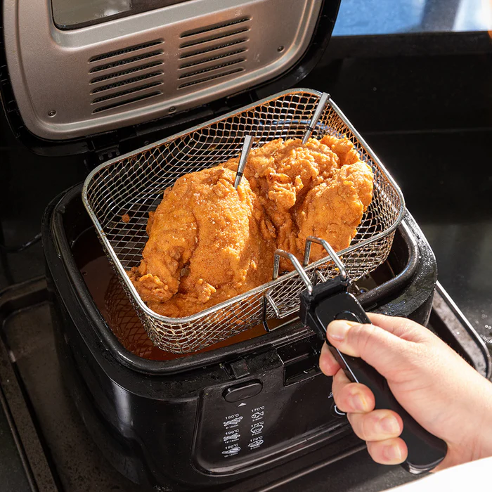 En hånd holder en frityrgryte med mat, mens Traeger Meater Pro XL - WiFi steketermometer sørger for perfekt tilberedning hver gang.