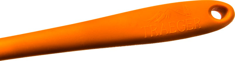 Nærbilde av Traeger Silicone Basting Brush - matpensel med oransje skaft, laget av varmebestandig silikon, med Traeger-logo og opphengshull i enden.