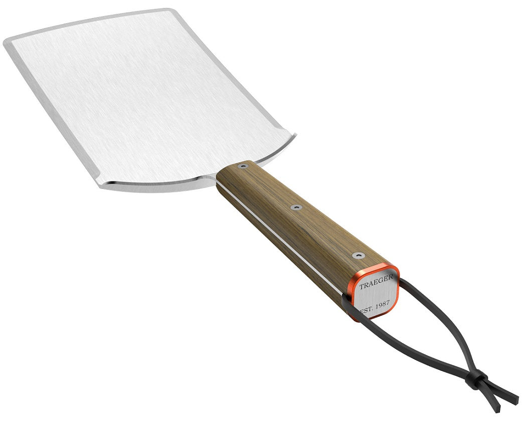 Traeger XXL BBQ Spatula fra Traeger har et bredt, rektangulært blad i rustfritt stål, et trehåndtak og en lærrem som er festet gjennom hullet i enden.