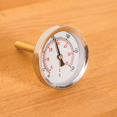 FastBrewing Termometer til FastFerment, et analogt termometer i metall for ølbrygging, sitter på tre og viser ca. 90 °C - ideelt ekstrautstyr for presis brygging.