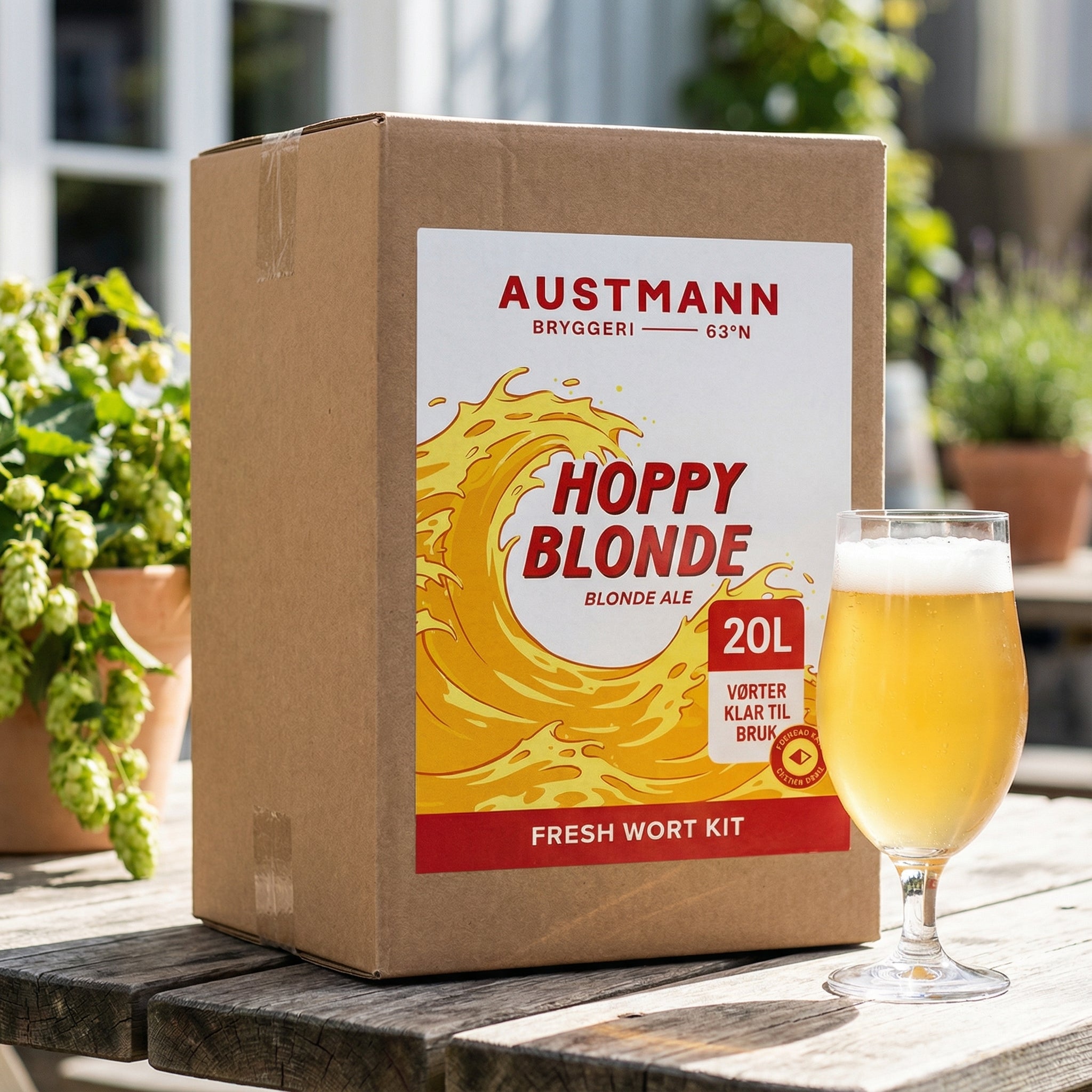 En pappeske merket Austmann Hoppy Blonde - 20L Fresh Wort Kit står på et bord utendørs ved siden av et glass lys belgisk blond ale.