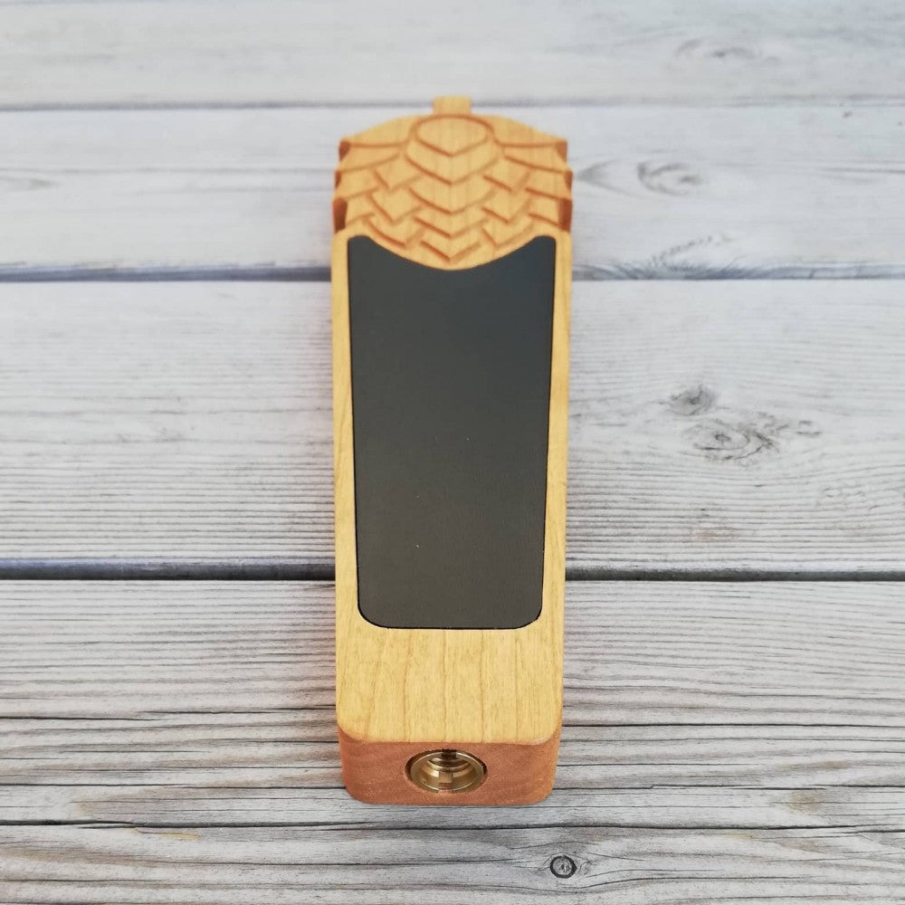 Et Hop Shaped Tap Handle fra Ouellette Wood Works, håndlaget i kirsebærtre med svart krittavle på toppen og utskåret mønster, plassert på en lys treflate.