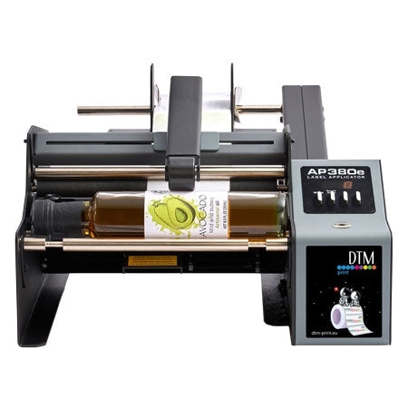 Primera AP380e etikettmaskin påsetter en avokadooljeetikett på en flaske; displayet viser Primera AP380e Label Applicator.