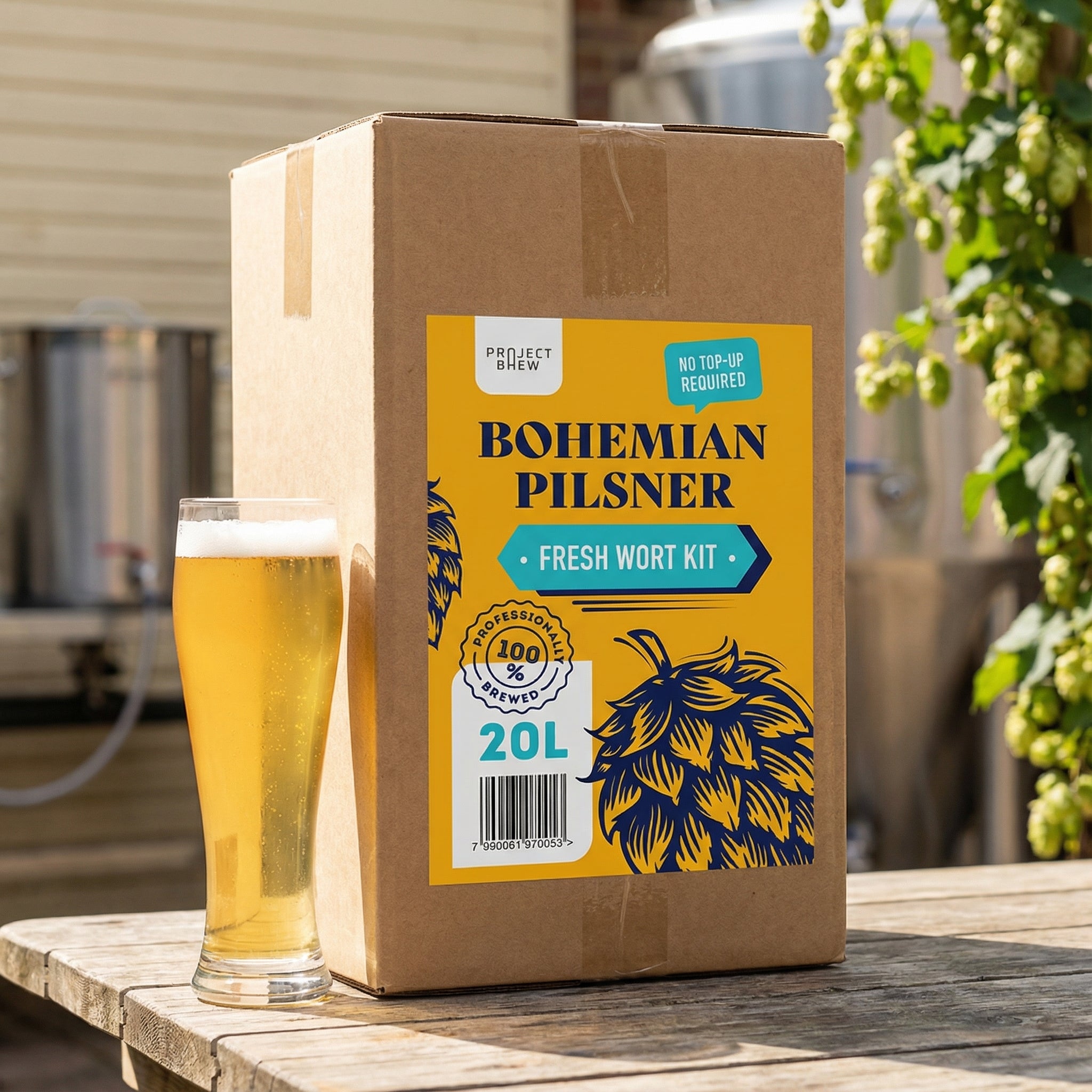 En pappeske merket Project Brew Bohemian Pilsner - 20L Fresh Wort Kit står ved siden av en halvliter øl utendørs, med profesjonelt brygget vørter og bryggeutstyr i bakgrunnen.