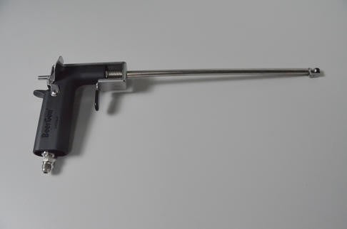 En svart og sølvfarget veterinærbolt med et langt metallrør, som matcher den elegante designen til Blichmann BeerGun flaskefyller fra Blichmann, ligger på en grå overflate.