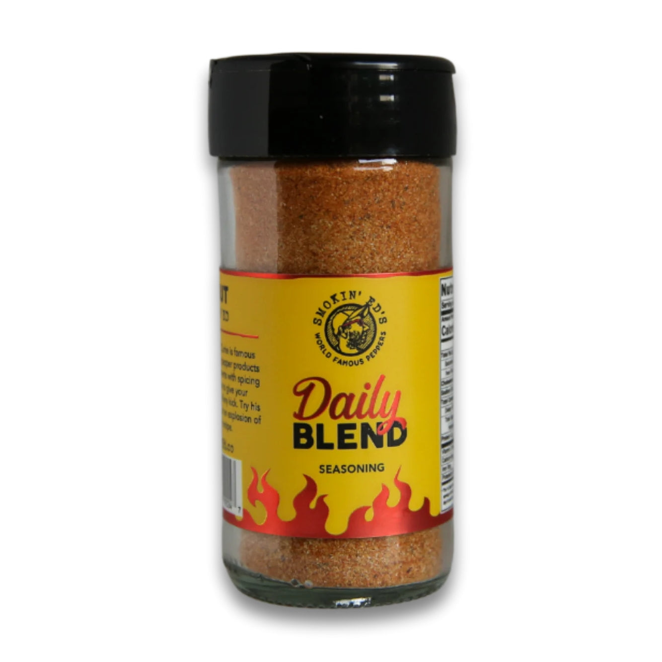 Et gjennomsiktig krydderglass merket Smokin' Ed's Daily Blend Seasoning fra PuckerButt Pepper Company, med gulrød etikett med flammer, svart lokk og kraftig krydder - perfekt til indiske curryretter eller for å tilføre Pepper X-hette til måltider.