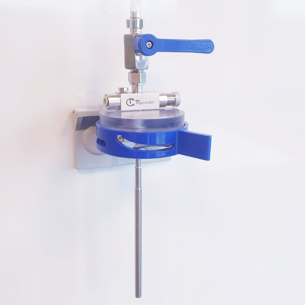 A Tapcooler Nanocanner IM - Boksfyller laboratorieventilapparat med metallhåndtak og lang stang koblet til et klart sirkulært kammer, montert på en hvit vegg. Merkevare: Tapcooler.
