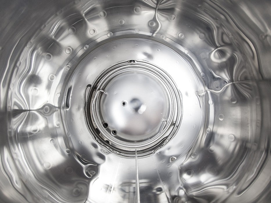Utsikt fra innsiden av en Speidel 50L #Braumeister PLUS, som viser sirkulære mønstre, refleksjoner og vanndråper på den glatte metalloverflaten med presis temperaturkontroll.