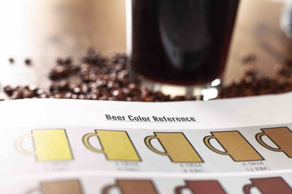 Nærbilde av et Beer Color Reference-diagram med et glass mørkt øl og kaffebønner i bakgrunnen - ideelt for øloppskrifter eller notater i Brewshop Brew Journal - bryggelogg.
