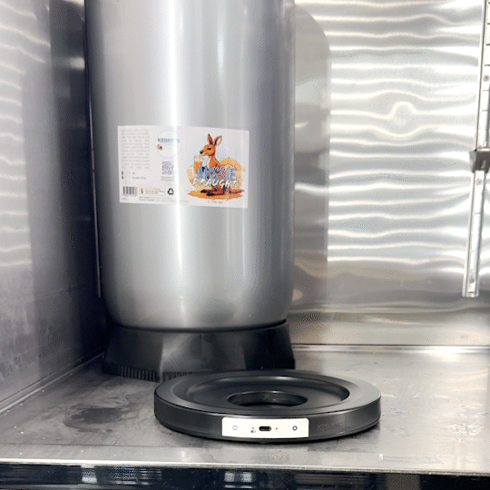 Et sylindrisk ølfat av metall med en kenguru-etikett står ved siden av en Keg King KegMaster KS1 KegScale - vekt til corneliusfat, begge plassert på en metallflate.