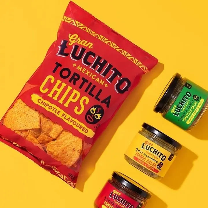 En pose med Gran Luchito Chipotle Tortilla Chips (150 g) står ved siden av tre glass med ulike Gran Luchito-salsaer fra Mexico på en gul bakgrunn.