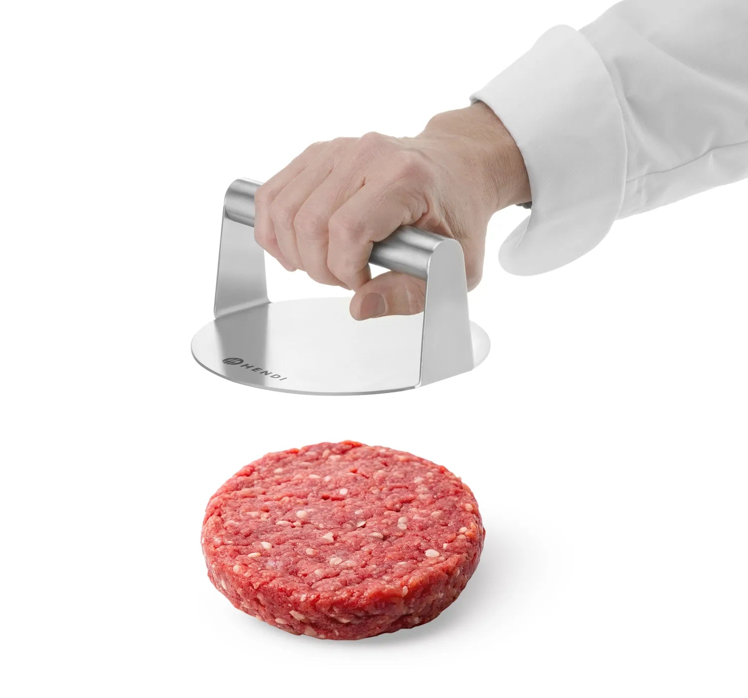 En person holder Hendi Smash Burger Presse i rustfritt stål over en rå biffbiff på en hvit flate.