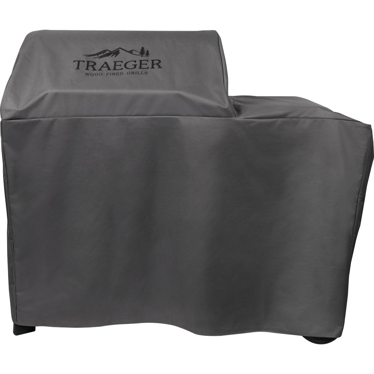 En vedfyrt grill fra Traeger beskyttes av det grå Traeger Grill Cover Woodridge - grilltrekk, som har et tilpasset, værbestandig design og Traeger-logoen på forsiden.