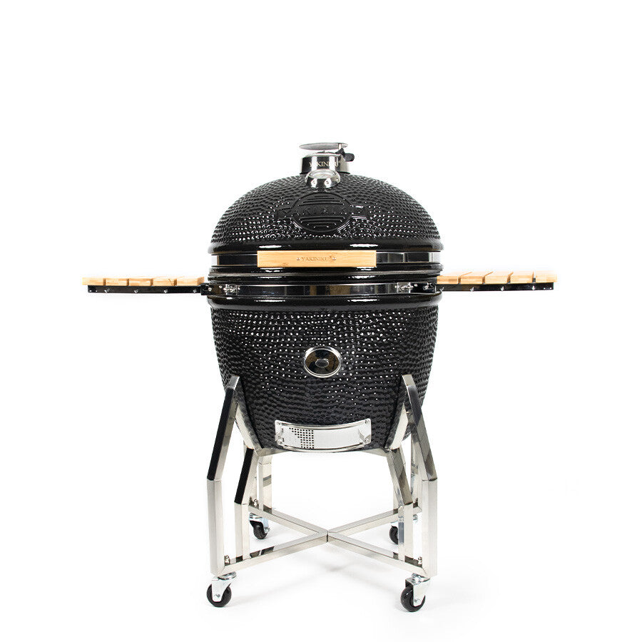 YAKINIKU Kamado XXLARGE Complete har en svart keramisk grill med kuppelformet lokk, to sidehyller i tre, et robust metallstativ og hjul. Dette komplette settet vises mot en vanlig hvit bakgrunn.